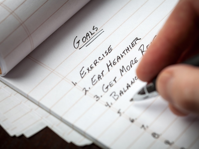 Define your goals and write them down. Someone writing a list of goals.