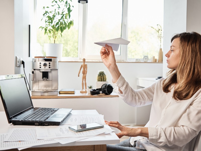 A disorganized woman procrastinating at her desk. A disorganized woman procrastinating at her desk.