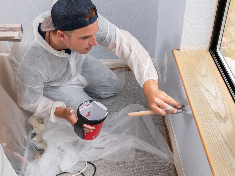 Identify the resources required to achieve your goal. Resources for painting and decorating: a painter equipped with materials and tools is painting a wall.